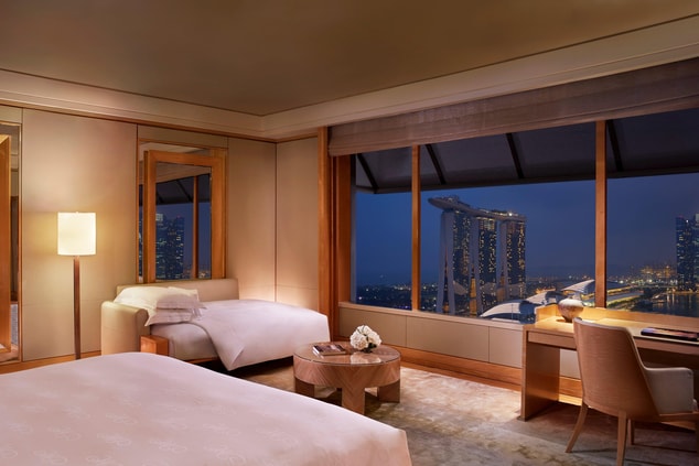 Guest room with plush daybed and views of Marina Bay.