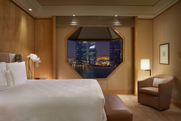 Suite with a King bed and an octagonal window overlooking views of Marina Bay.